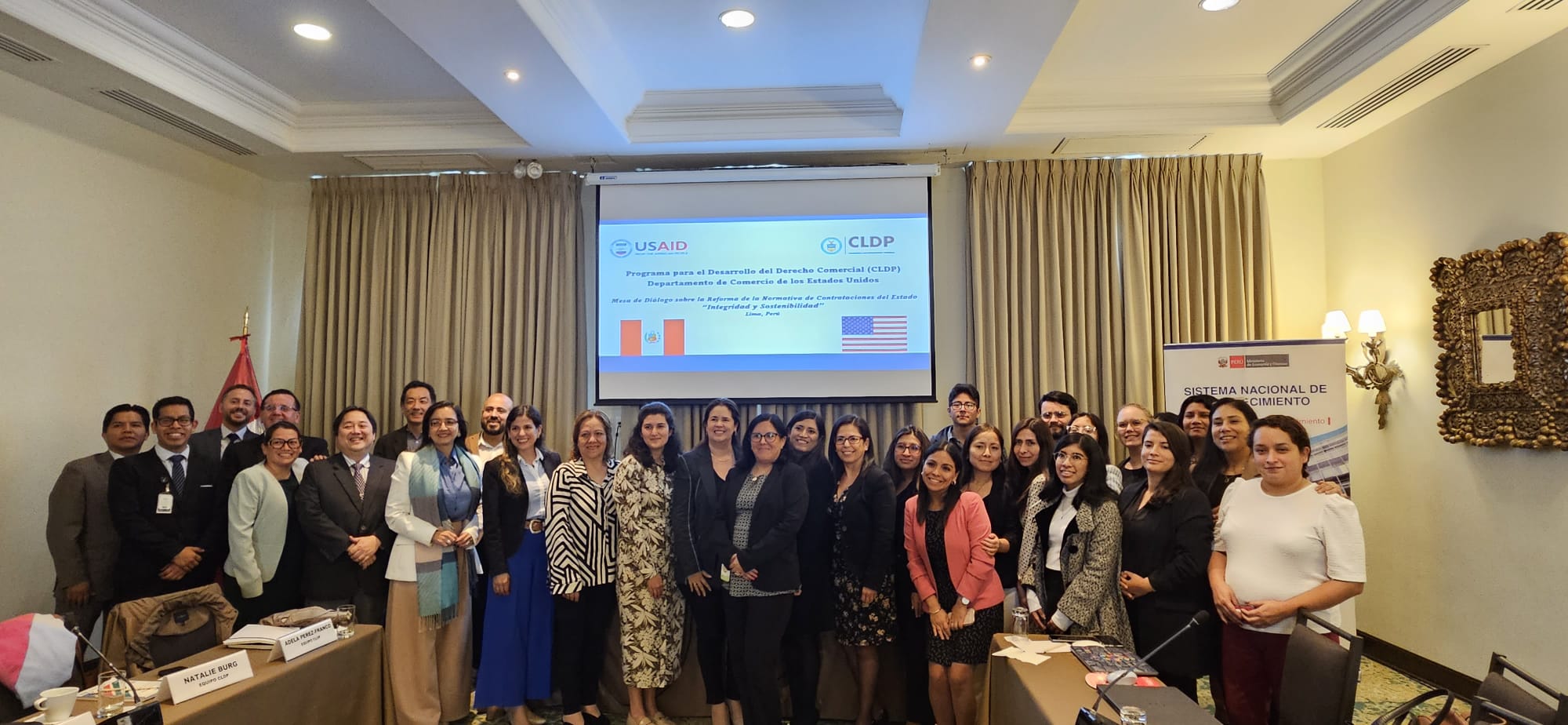 Group of people standing and smiling in two rows.