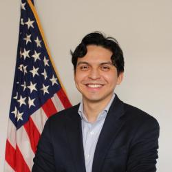 Official headshot with U.S. flag in the background.