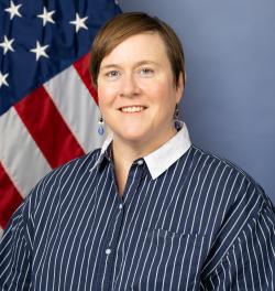 Portrait of a woman wearing a striped button up in front of a background
