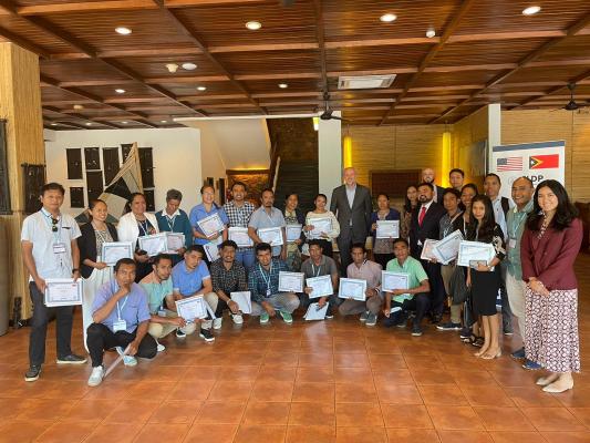 Group photo of participants from the Timor-Leste Workshop. Participants are holding their certificates and smiling.